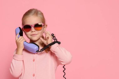 Pembe arka planda cep telefonu olan şirin küçük bir kız. Mesaj atmak için yer var.