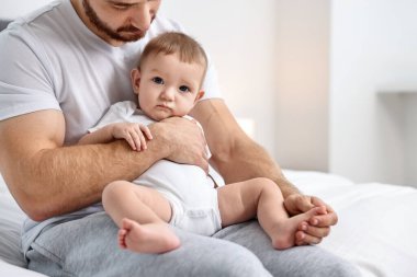 Babası küçük bebeğiyle evde, yatakta, yakın plan.