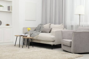 Oturma odasında battaniyeli, koltuklu ve lambalı rahat bir kanepe. İç tasarım