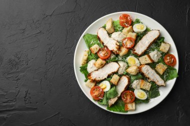 Lezzetli Sezar salatası, tavuklu ve domatesli siyah masa, üst manzara. Metin için boşluk