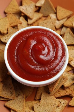 Ketchup in bowl and pieces of dry bread on plate, closeup clipart