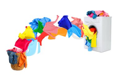 Temiz renkli giysiler çamaşır makinesinden beyaz arka planda çamaşır sepetine uçuyor.