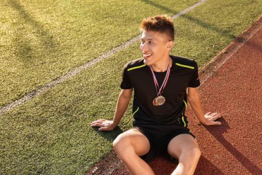 Mutlu kazanan farklı madalyalarla güneşli bir günde stadyumda oturuyor. Metin için boşluk