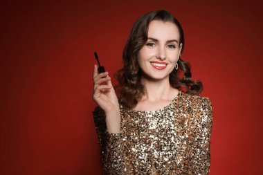 Kırmızı arka planda makyaj fırçası olan gülümseyen kadın. Metin için boşluk