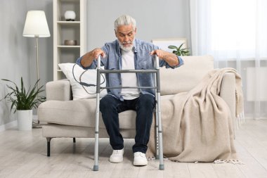 Evdeki kanepede yürüyen yaşlı adam.