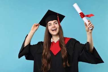 Mezuniyetten sonra açık mavi arka planda diplomalı mutlu bir öğrenci.