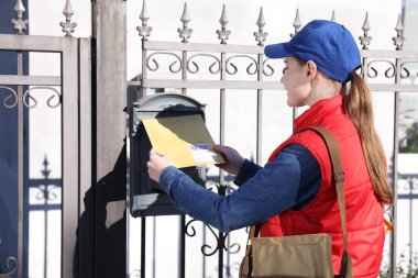 Postacı zarfı dışarıdaki posta kutusuna koydu.