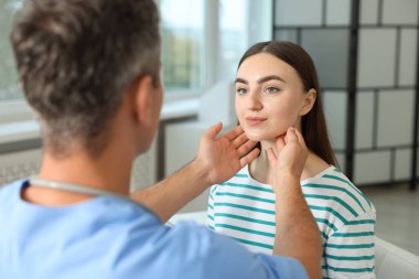 Randevu sırasında klinikte kadının boğazını muayene eden doktor.