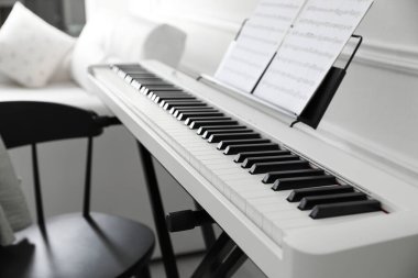 Synthesizer with music sheets and chair at home, closeup clipart