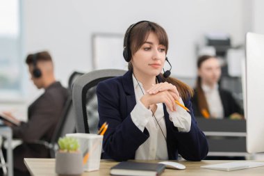 Satıcı kadın ofiste kulaklıkla müşteriyle konuşuyor.