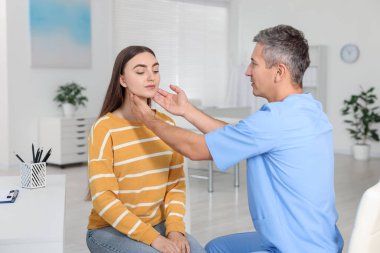 Randevu sırasında klinikte kadının boğazını muayene eden doktor.