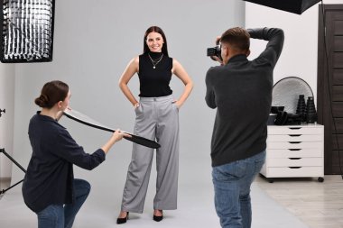 Profesyonel fotoğraf stüdyosunda modelle çalışan fotoğrafçı ve asistan.