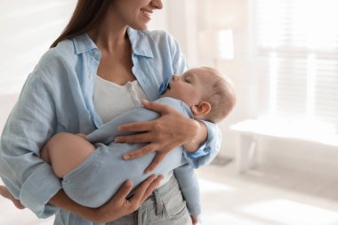 Anne uyuyan bebeğini kucağında tutuyor, yakın plan. Metin için boşluk