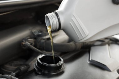 Araba motoruna motor yağı dökülüyor, yakın plan.