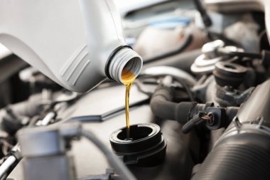 Araba motoruna motor yağı dökülüyor, yakın plan.