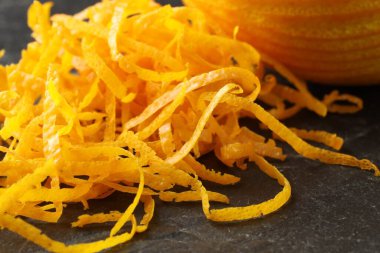 Fresh orange zest and fruit on black table, closeup clipart