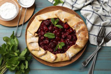 Açık mavi ahşap masada servis edilen kirazlı leziz bir galet.