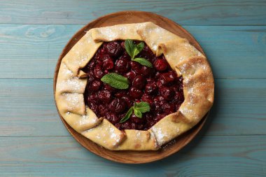 Kirazlı leziz galette ve açık mavi ahşap masa, üst manzara.
