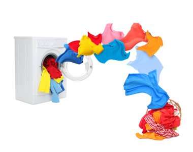 Temiz renkli giysiler çamaşır makinesinden beyaz arka planda çamaşır sepetine uçuyor.