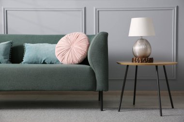 Rahat bir kanepe ve gri duvarın yanındaki yan masa.