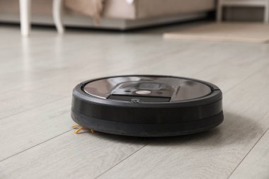 Robotik süpürge, ahşap zeminde, kapalı alanda.