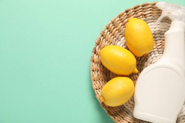 Turkuaz arka planda bir şişe temizlik malzemesi ve limon, üst manzara. Metin için boşluk