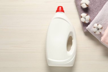 Çamaşır deterjanı şişesi, temiz havlular ve tahta arka planda pamuk çiçekleri.