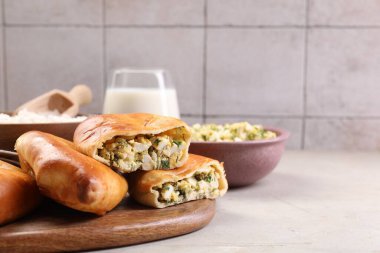 Delicious pirozhki (stuffed pastry pies) and ingredients on grey table, closeup clipart