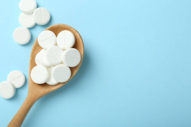 Antibiyotik haplar ve açık mavi arka planda kaşık. Metin için boşluk