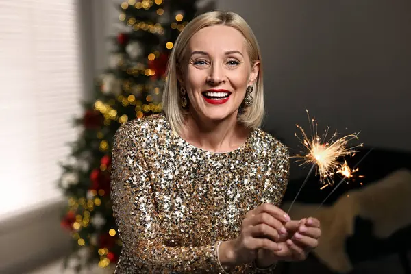 Evde Noel 'i kutlayan maytaplı, gülümseyen kadın.
