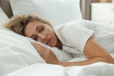 Menopoz, uyku sorunları. Yatakta uykusuzluk çeken bir kadın.