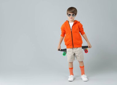 Açık gri arka planda kaykaylı küçük çocuk, mesaj için boşluk