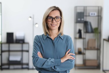 Ofiste kollarını kavuşturmuş mutlu bir iş kadını portresi.