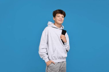 Açık mavi arka planda sırt çantalı genç bir çocuk.