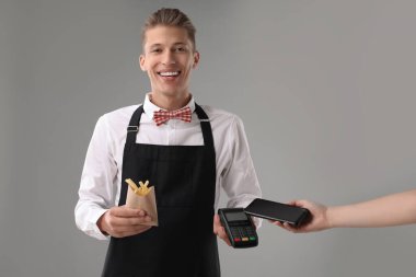 Fast-food işçisi müşterisinden gri arka plan üzerinden ödeme alıyor, yakın plan