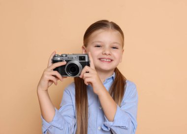 Bej arka planda fotoğrafçı gibi davranan kameralı küçük kız. Geleceğin mesleğini hayal etmek