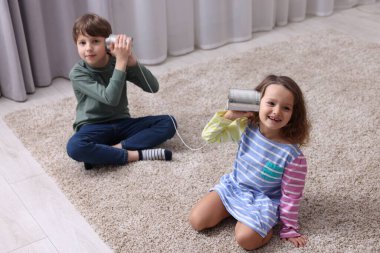 Teneke kutu kullanan kız ve erkek kapalı alanda telefon eder.