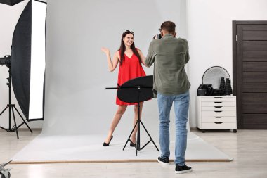 Profesyonel fotoğraf stüdyosunda modelle çalışan bir fotoğrafçı.