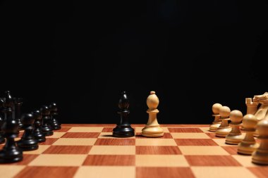 Satranç tahtasındaki diğer satranç taşlarının yanındaki siyah ve beyaz piskoposlar yakın plan. Rekabet konsepti