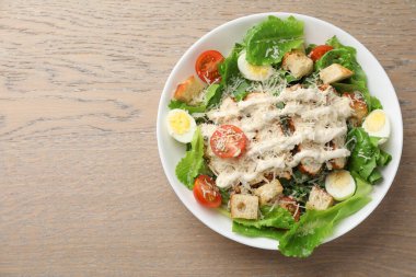 Lezzetli Sezar salatası, tavuklu ve ahşap masada domatesli, üst manzara. Metin için boşluk