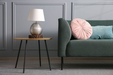 Rahat bir kanepe ve gri duvarın yanındaki yan masa.