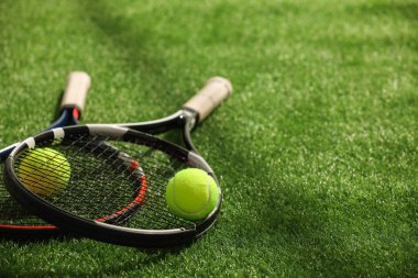 Tenis raketleri ve topları yeşil yapay çimlerde, metin için alan