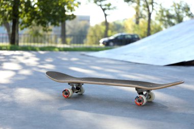 One modern skateboard with black griptape in skatepark clipart