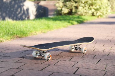 One modern skateboard on paved pathway outdoors clipart