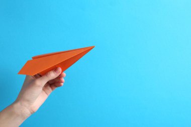 Açık mavi arka planda el yapımı kağıt uçaklı bir kadın, yakın plan. Metin için boşluk
