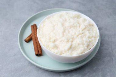 Gri masadaki tarçın çubuklu lezzetli sütlaç, yakın plan.