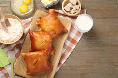 Lezzetli pirozhki (dolgulu börek) ve ahşap masa üzerindeki malzemeler, düz yatak. Metin için boşluk