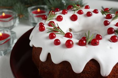 Güzel dekore edilmiş Noel pastası ve beyaz masada yanan mumlar, yakın plan.