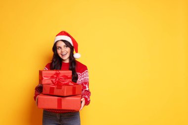 Noel Baba şapkalı kadın sarı arka planda Noel hediyeleri, mesaj için yer