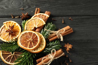 Farklı baharatlar, kurumuş portakal dilimleri ve siyah ahşap masa üzerinde köknar ağacı dalları, yukarıda yazı için yer var. Noel sezonu
